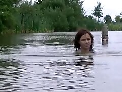 girl with fully clothes swims in lake